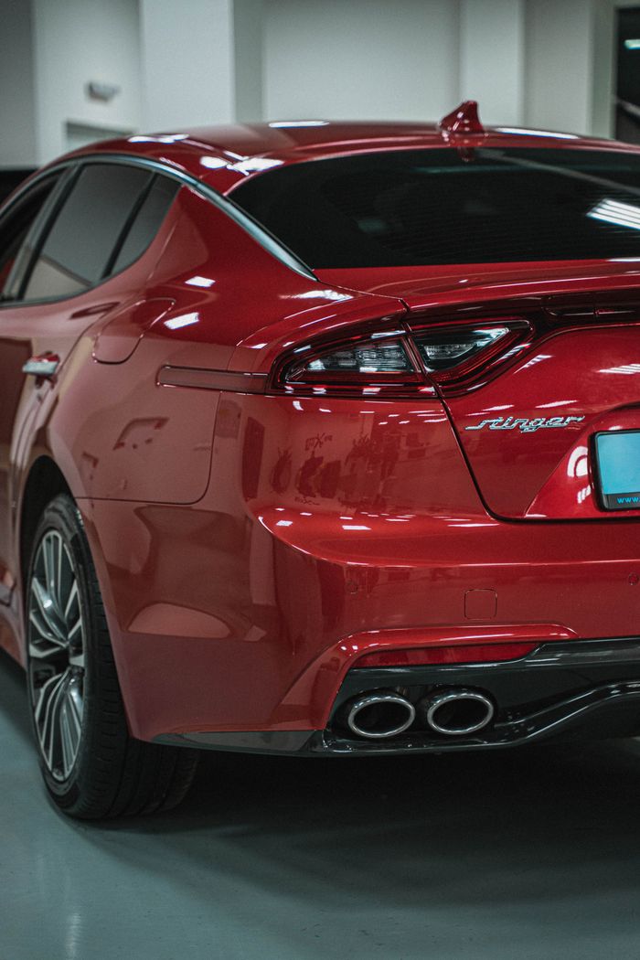 Stylish red sports car captured indoors showcasing a modern taillight and exhaust design.