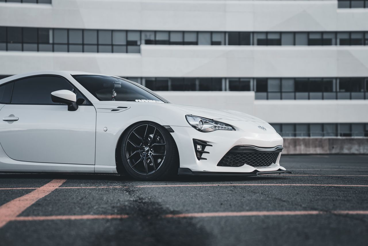 A sleek white sports car parked in a modern urban area, showcasing stylish design.